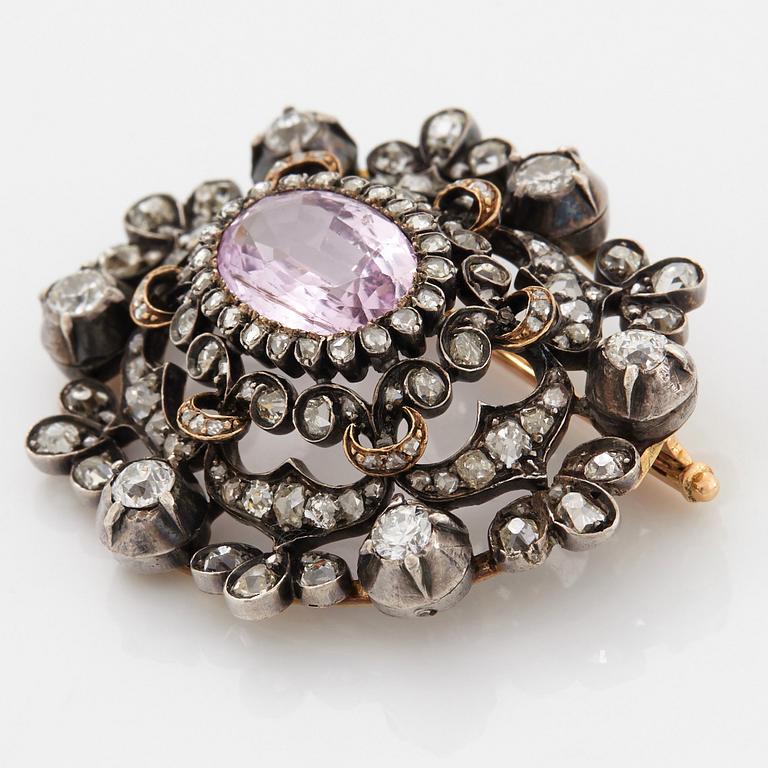 A 14K gold and silver brooch set with an oval faceted pink topaz and old- and rose-cut diamonds.