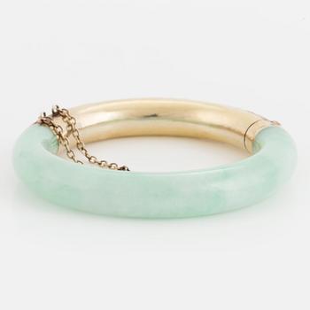 A jade bangle with a gilded silver clasp.