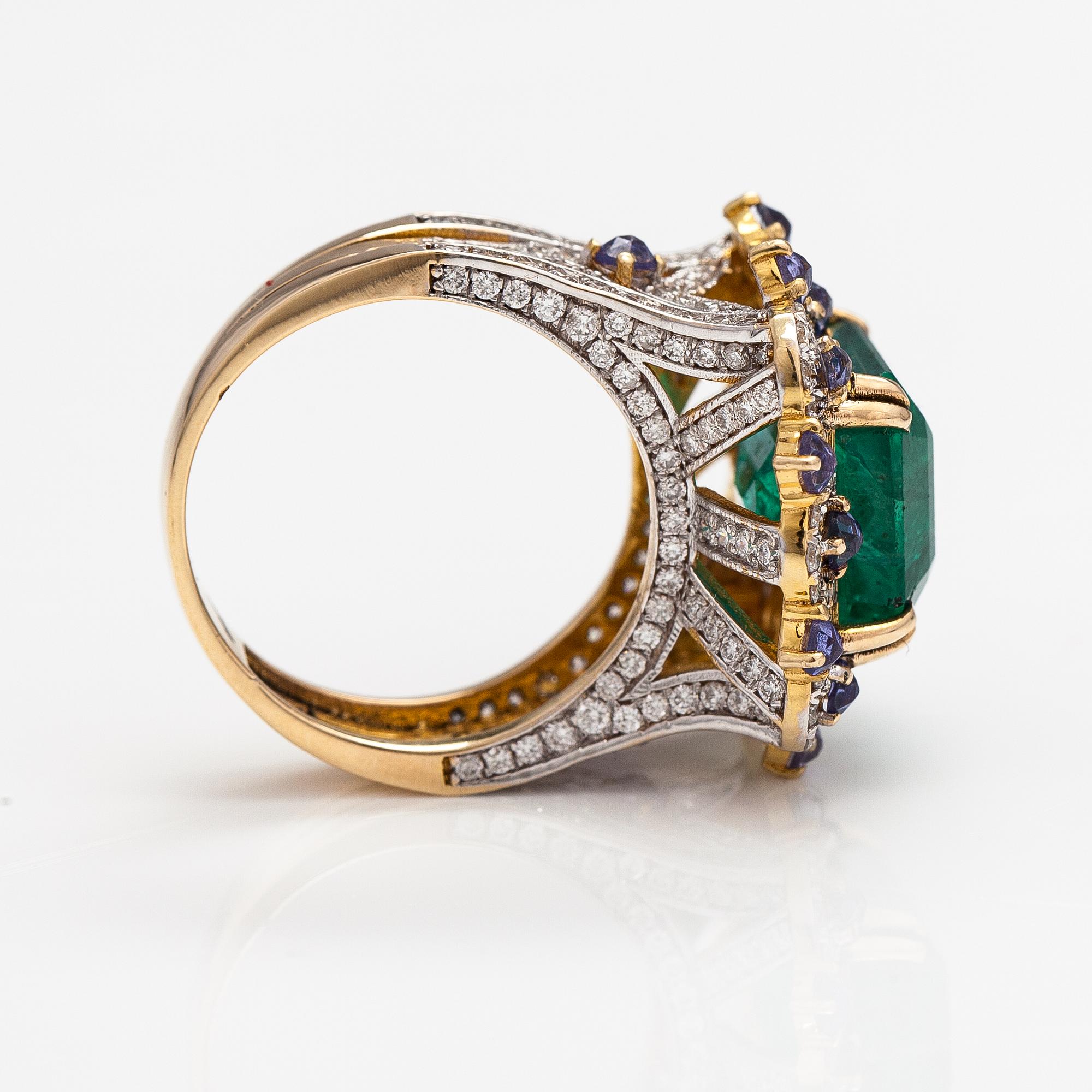 A 14k gold ring with an emerald ca. 6.39 ct, tanzanites and diamonds ca. 1.25 ct in total.