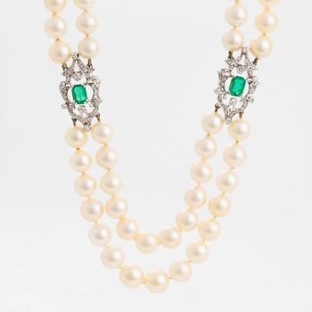 A two strand cultured pearl necklace clasp in 18K white gold set with a faceted emerald.