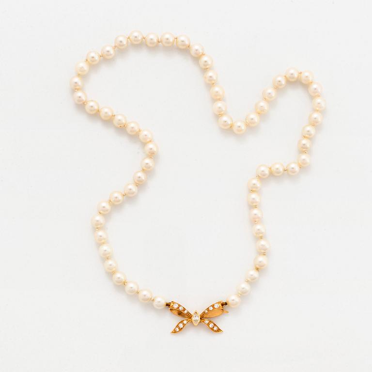 A cultured pearl necklace with a bow clasp in 18K gold set with round brilliant-cut diamonds.