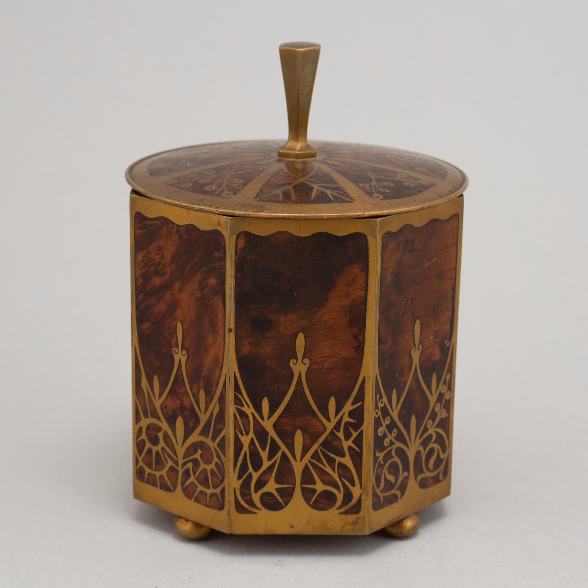 An art nouveau brass and burr walnut tobacco jar and cover from around year 1900.