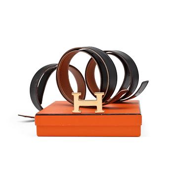 311. HERMÈS, four reversible belts, black and brown with gold coloured H belt buckle.