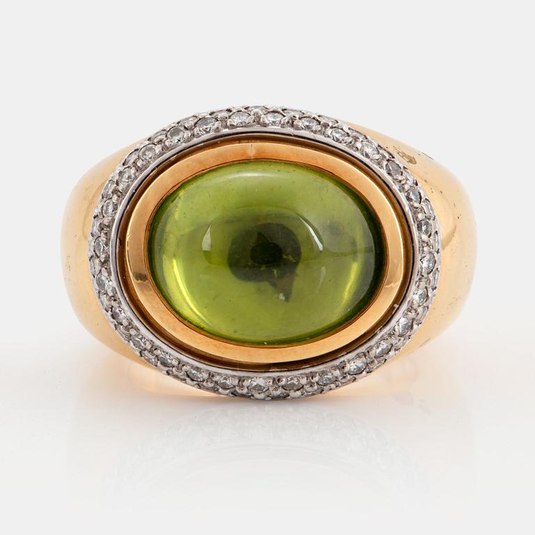 An 18K gold Steinlin ring set with a cabochon-cut peridot and round brilliant-cut diamonds.