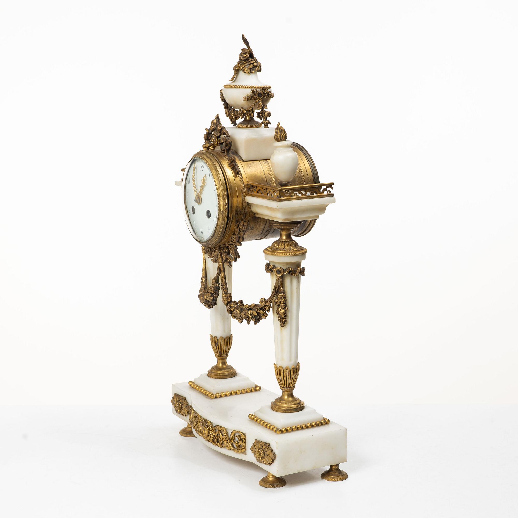 A Louis XVI-style mantle clock and a pair of candelabras. Early 20th century.