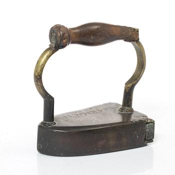 A brass clothes iron, dated 1710.