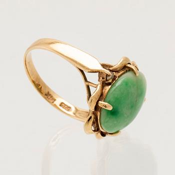 Ring in 14K gold with a green oval cabochon-cut stone and round brilliant-cut diamonds.