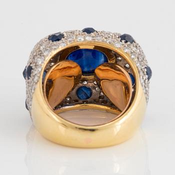 An 18K gold ring set with a cabochon-cut sapphire and round brilliant-cut diamonds and faceted sapphires.