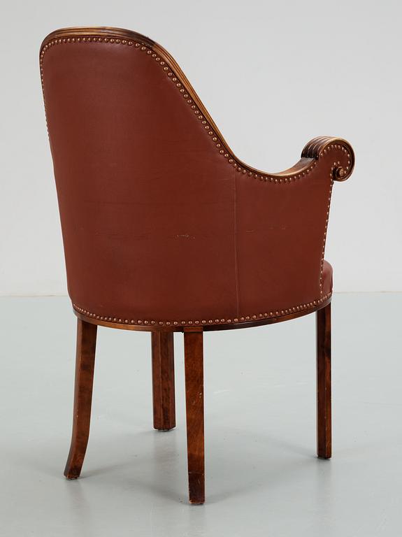 A Swedish easy chair in stained birch, upholstered in artificial leather, by NK, Nordiska Kompaniet, 1910's-20's.