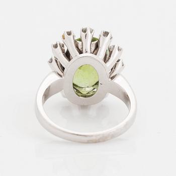 An 18K white gold ring set with a faceted peridot and round brilliant-cut diamonds.